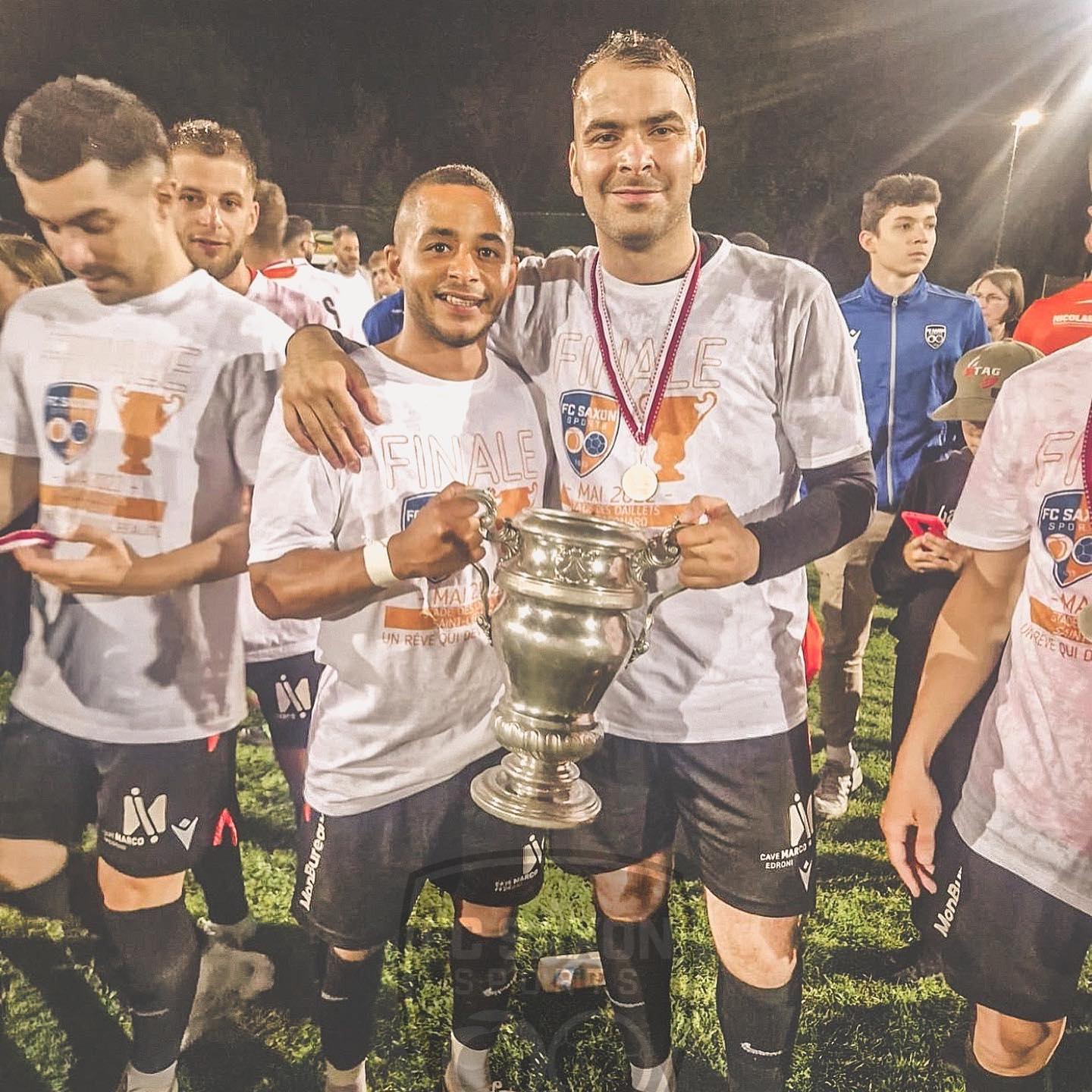 Un groupe de joueurs de football pose avec un trophée