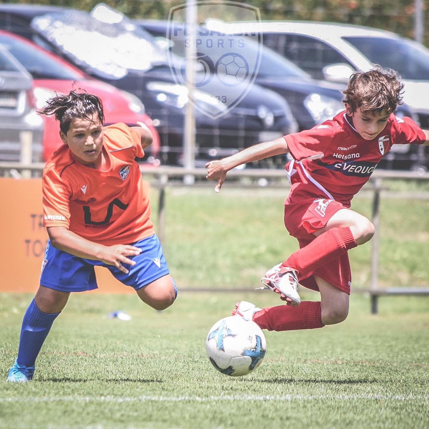 Deux jeunes garçons jouent au football sur un terrain.