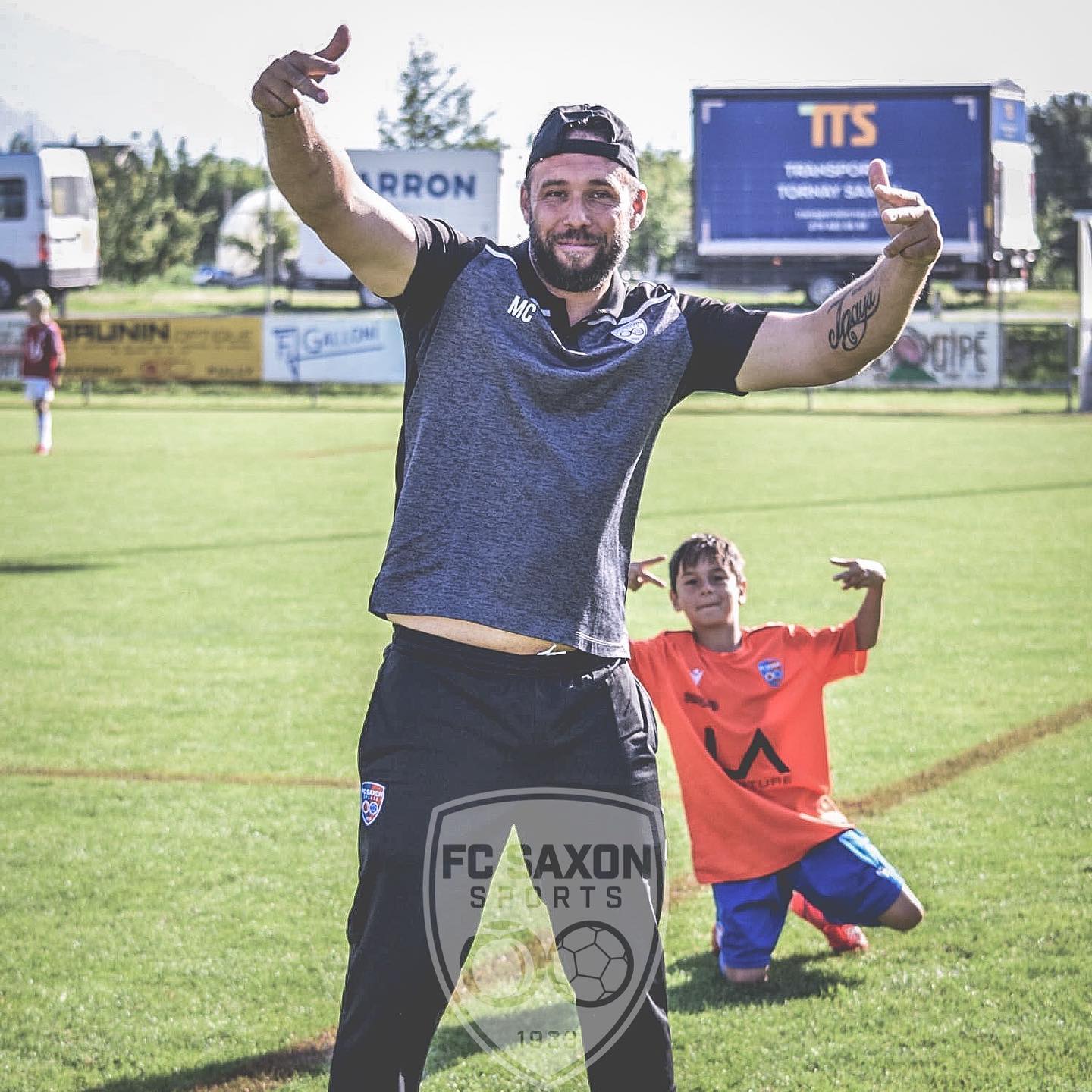 Un homme et un garçon sur un terrain de football avec un logo fc axon sports en arrière-plan