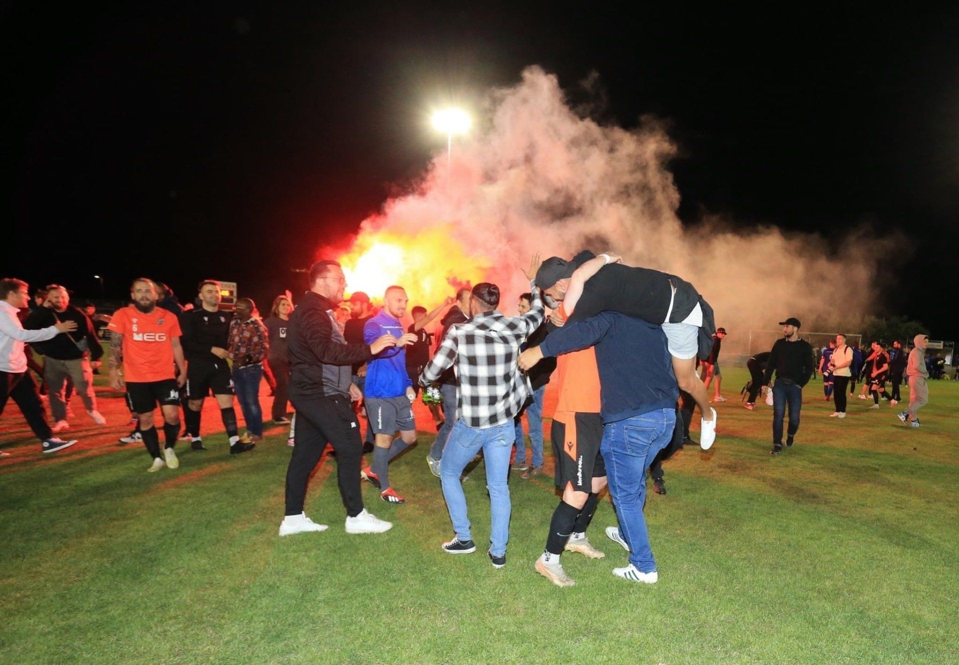 Un groupe de personnes se tient dans un champ avec de la fumée sortant du sol.