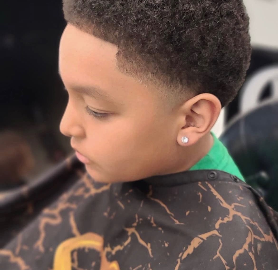 A young boy is getting his hair cut at a barber shop.