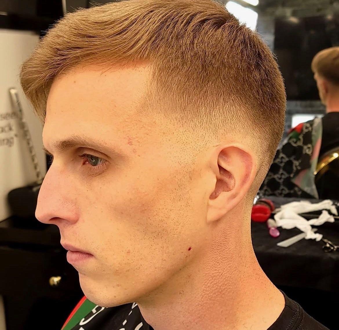 A man is getting his hair cut at a barber shop.