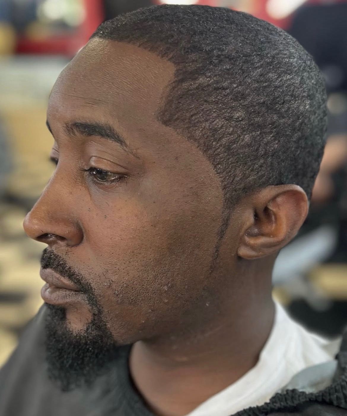 A man with a beard is getting his hair cut at a barber shop.