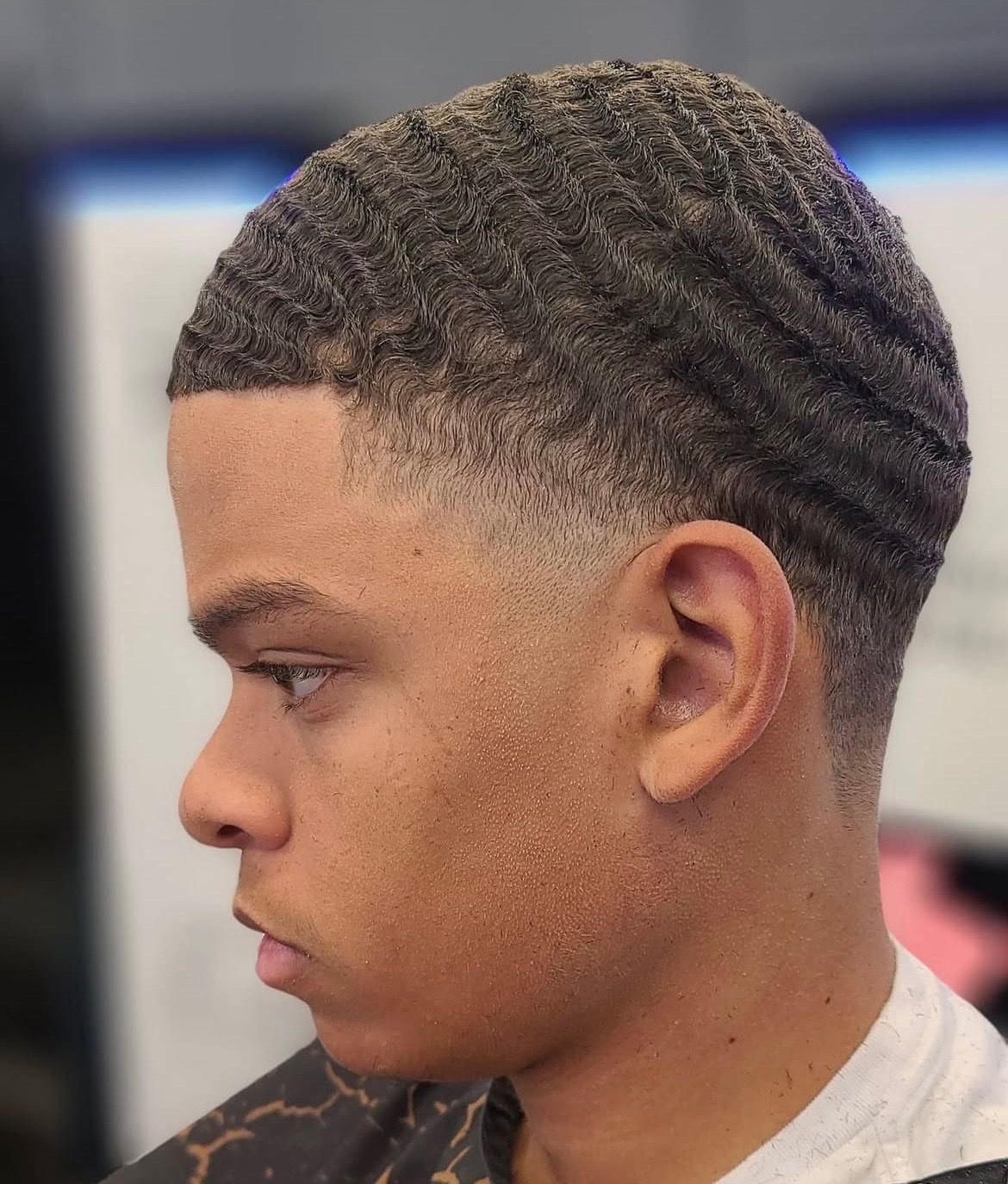 A young man is getting his hair cut at a barber shop.