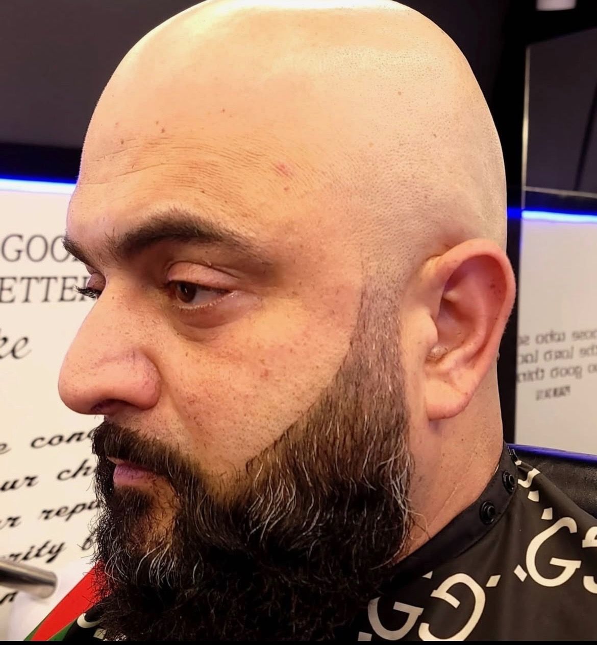 A bald man with a beard is wearing a gucci cape