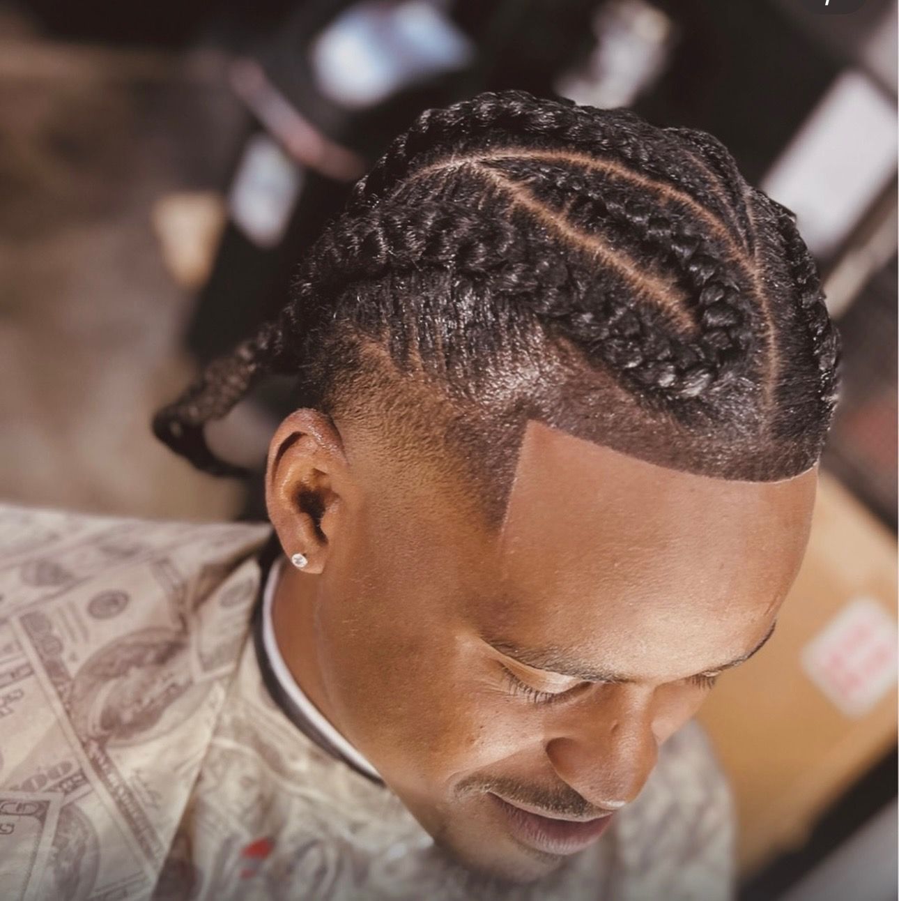 A man is getting his hair braided in a barber shop