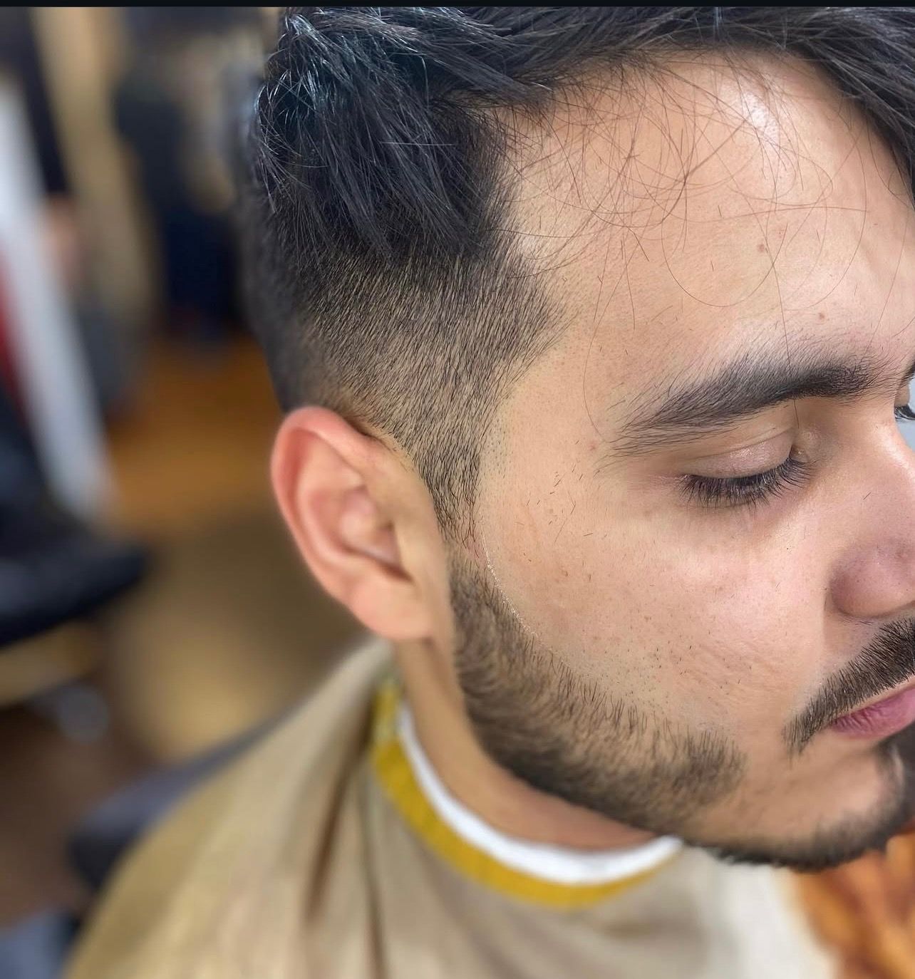 A man with a beard is getting his hair cut