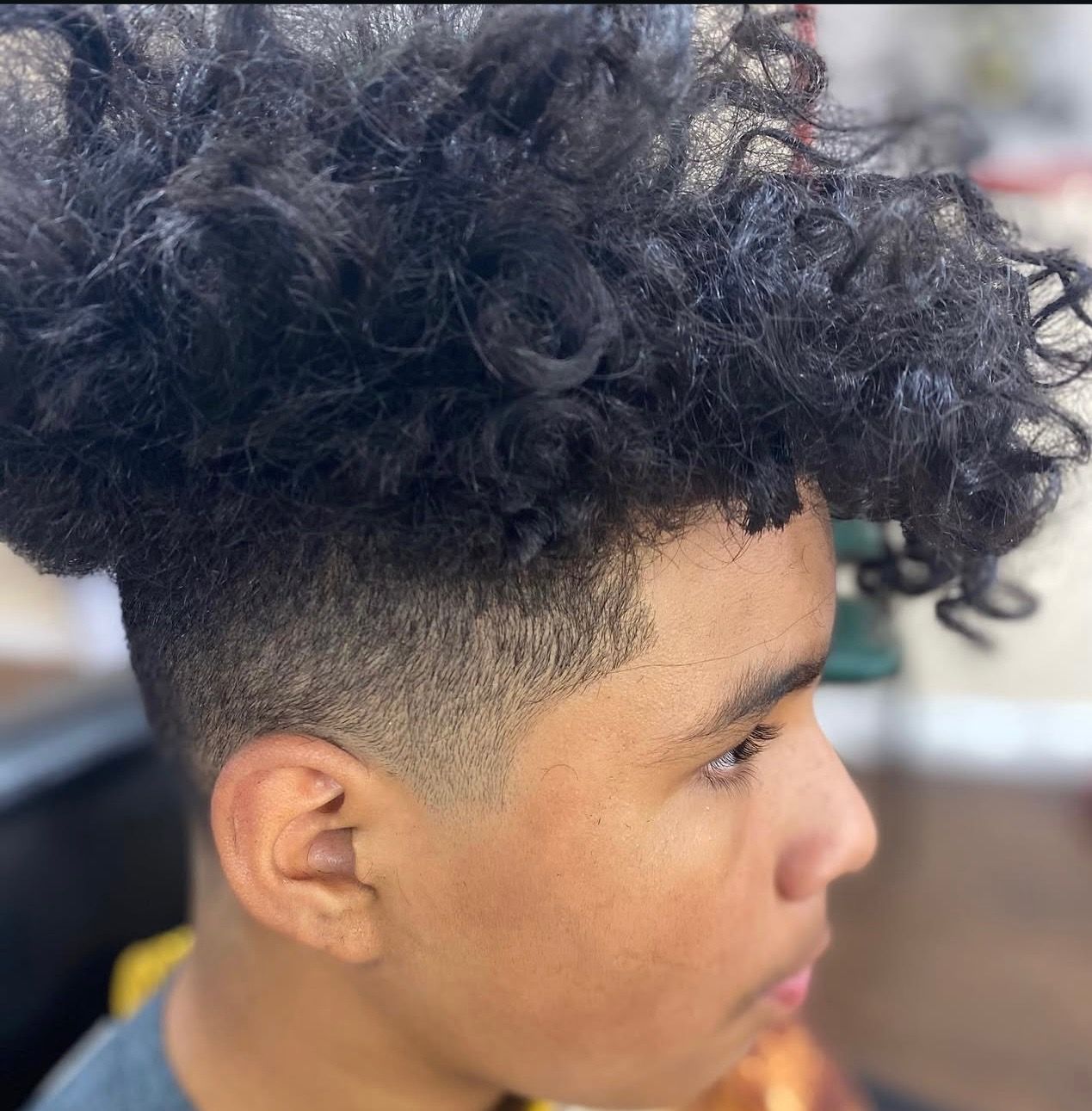 A young man with curly hair has a shaved head