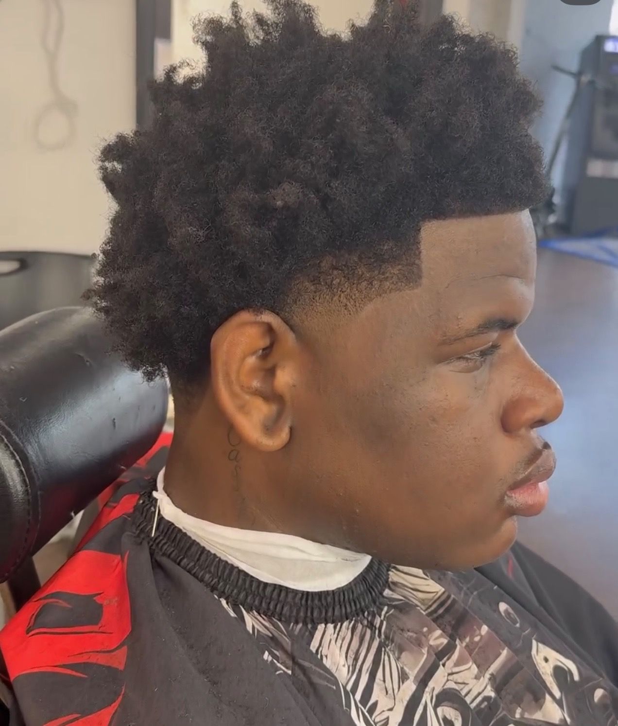 A young man is getting his hair cut at a barber shop.