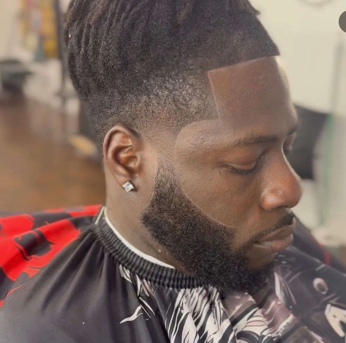 A man with a beard is getting his hair cut by a barber.