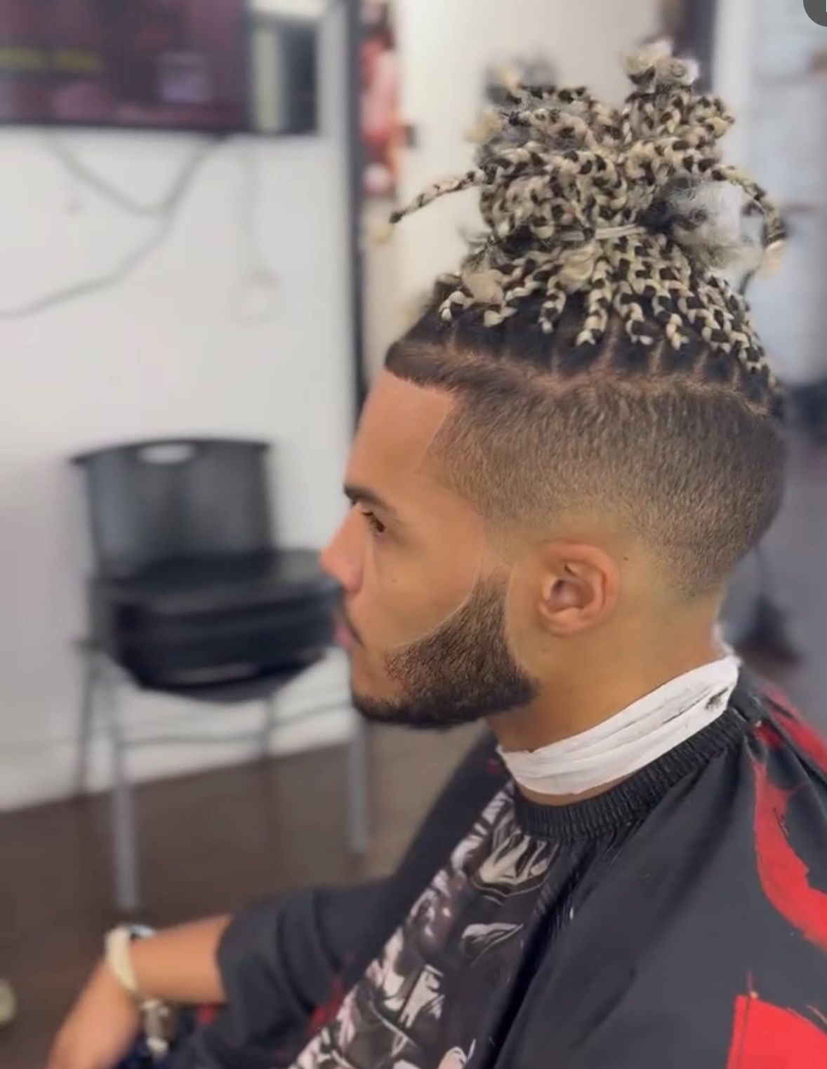 A man with dreadlocks and a beard is getting his hair cut