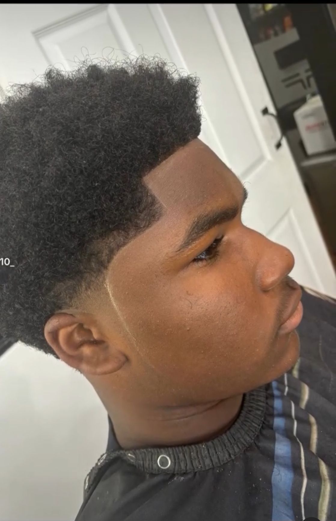 A young man is getting his hair cut by a barber.