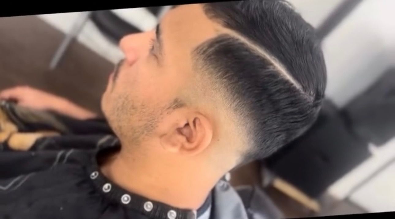A man is getting his hair cut at a barber shop.