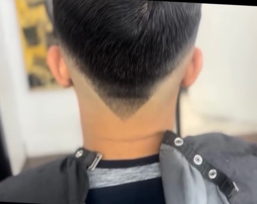 A man is getting his hair cut by a barber in a barber shop.