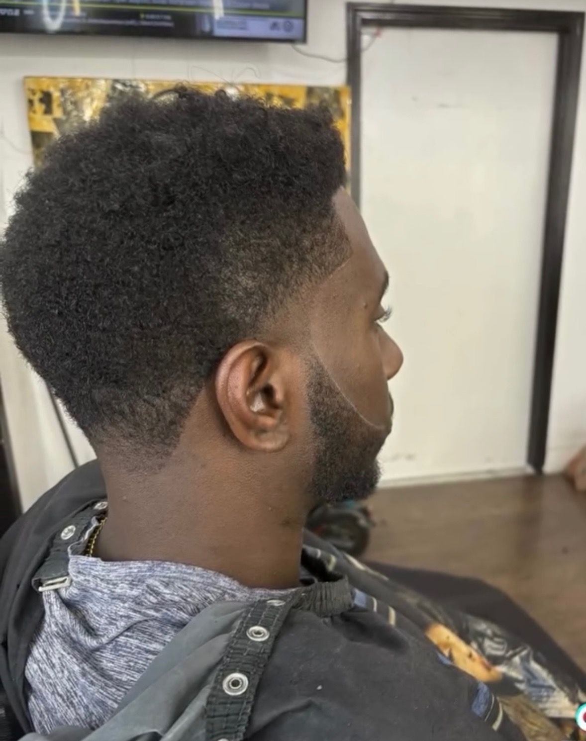 A man with a beard is getting his hair cut at a barber shop.