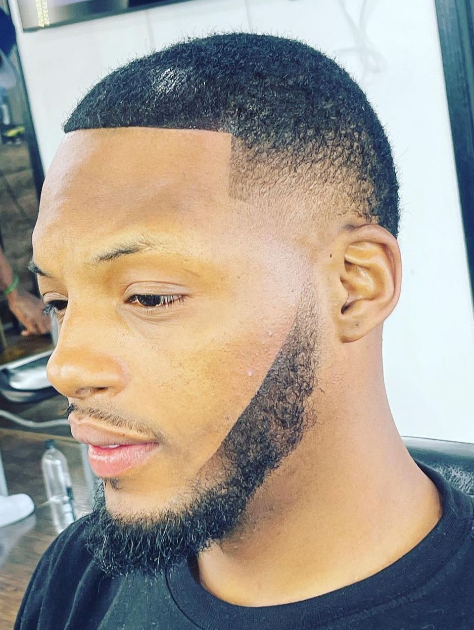 A man with a beard is getting his hair cut at a barber shop.