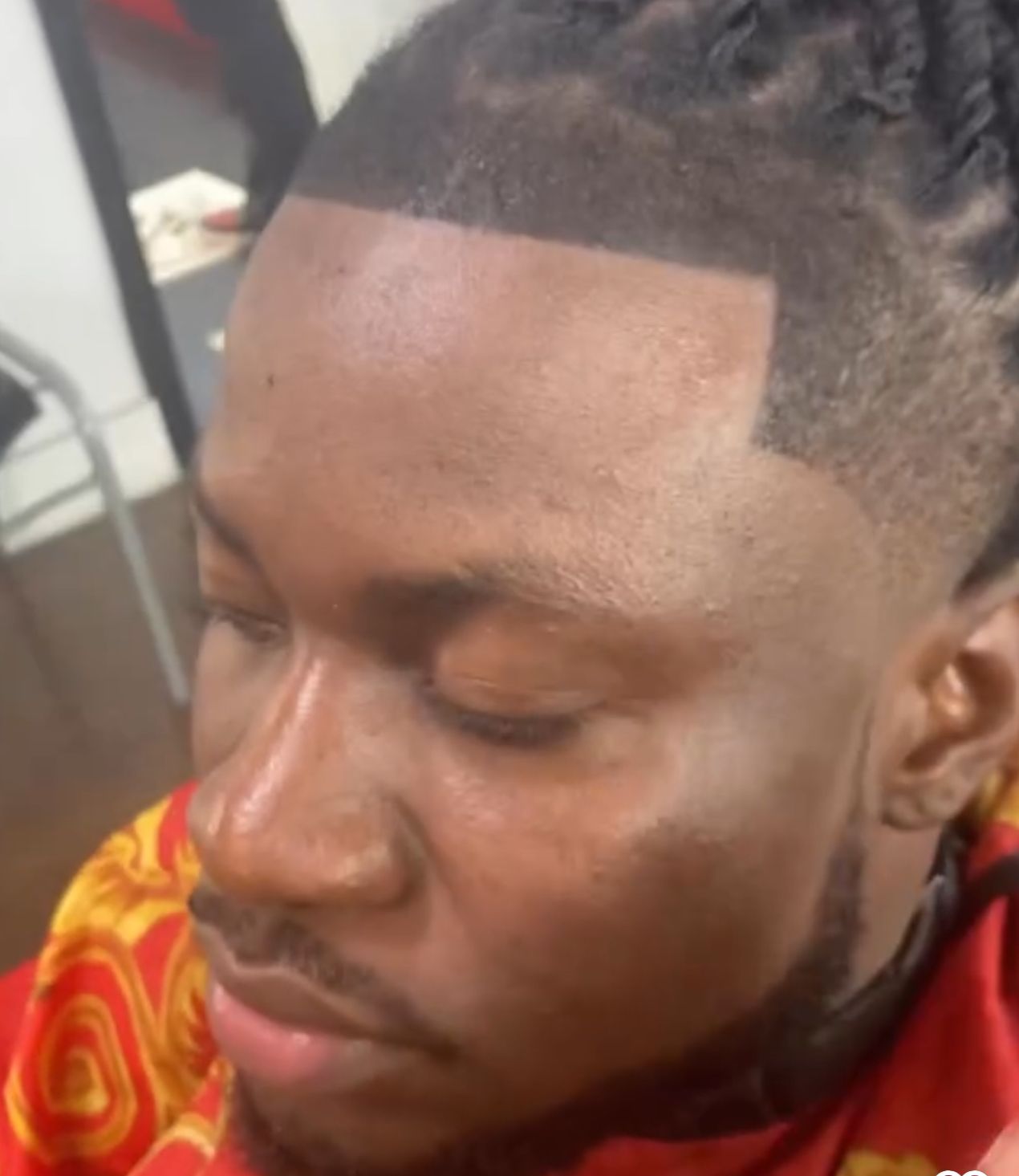 A man with dreadlocks and a beard is getting his hair cut at a barber shop.