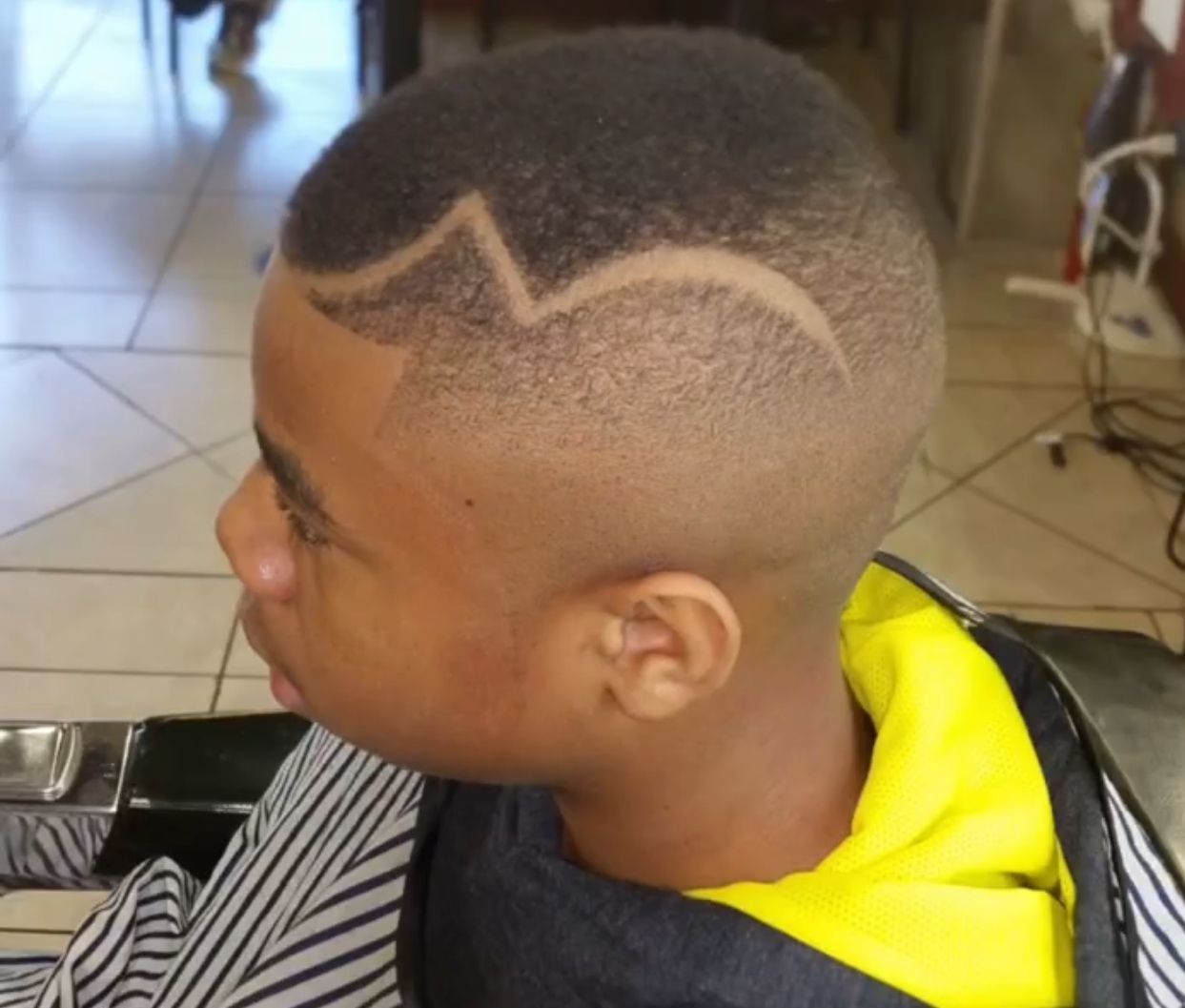 A young boy is getting his hair cut by a barber