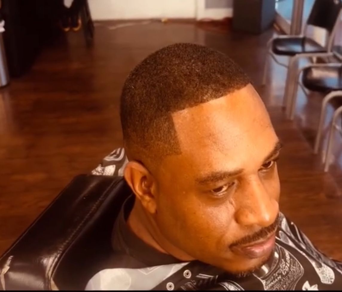 A man is sitting in a chair getting his hair cut