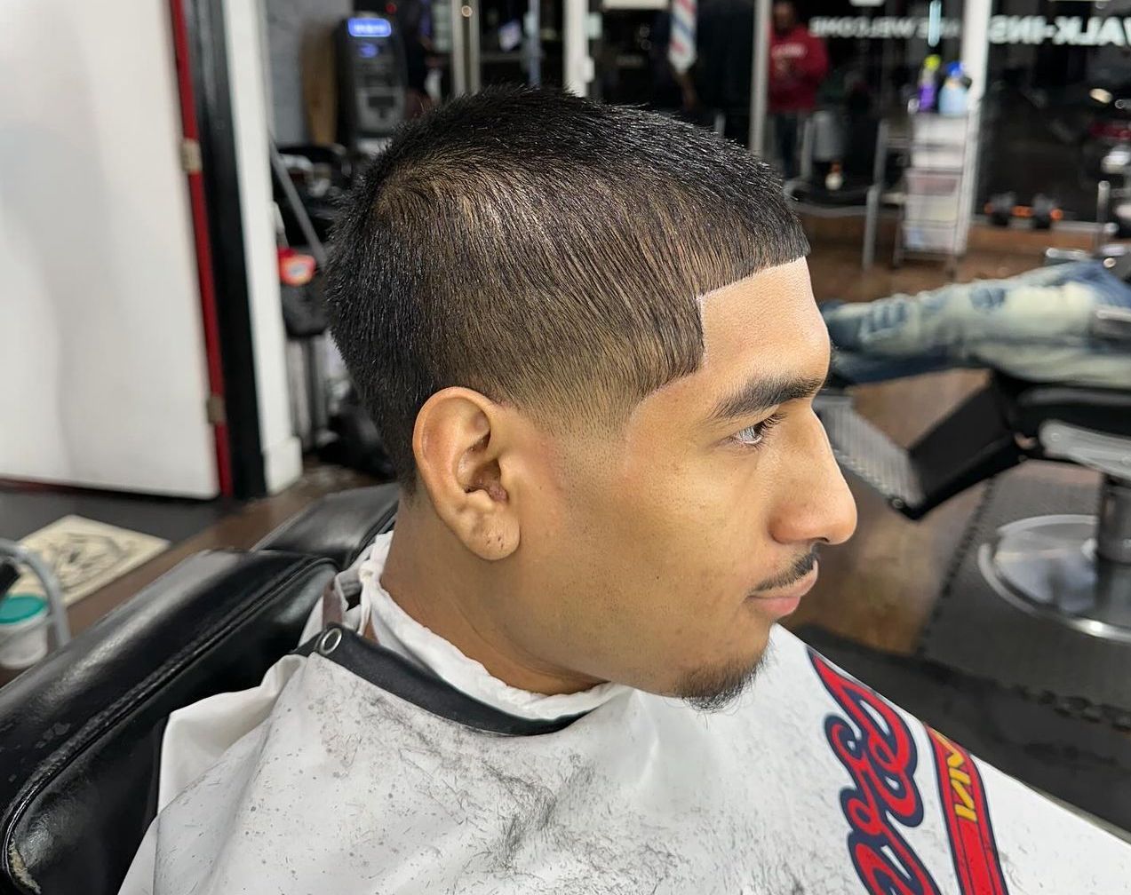 A man is getting his hair cut at a barber shop.