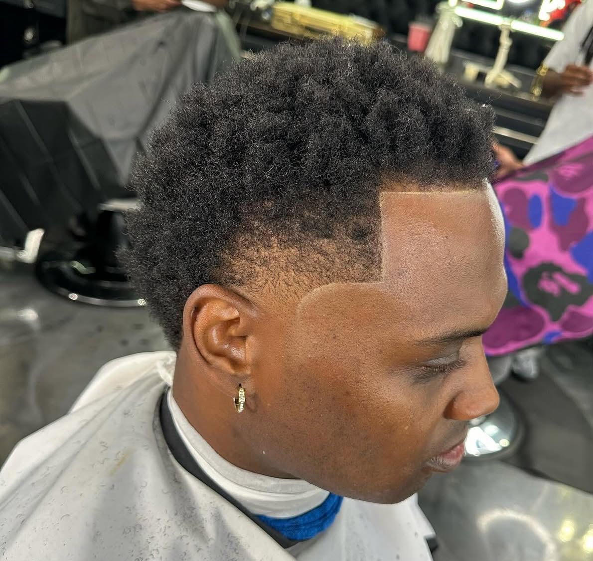 A man is getting his hair cut at a barber shop.