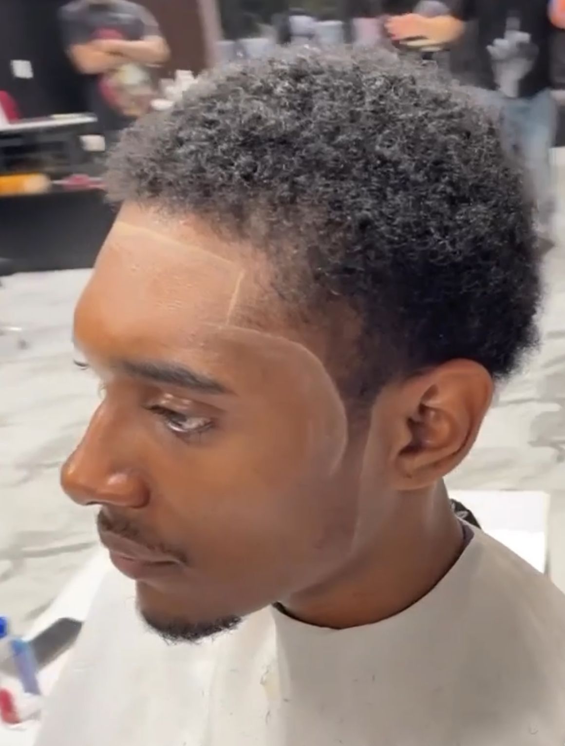 A man is getting his hair cut at a barber shop.