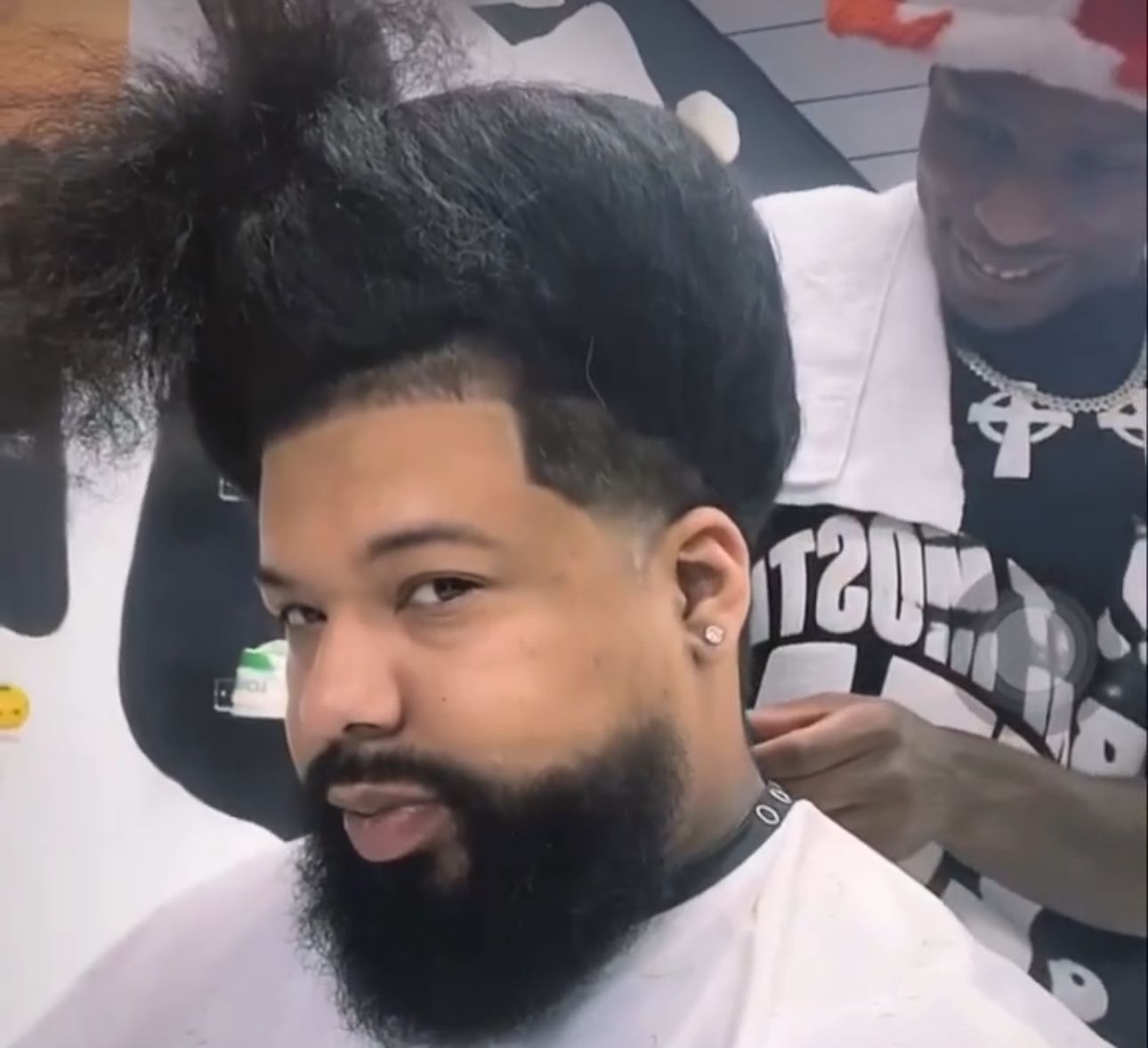 A man with a beard is getting his hair cut