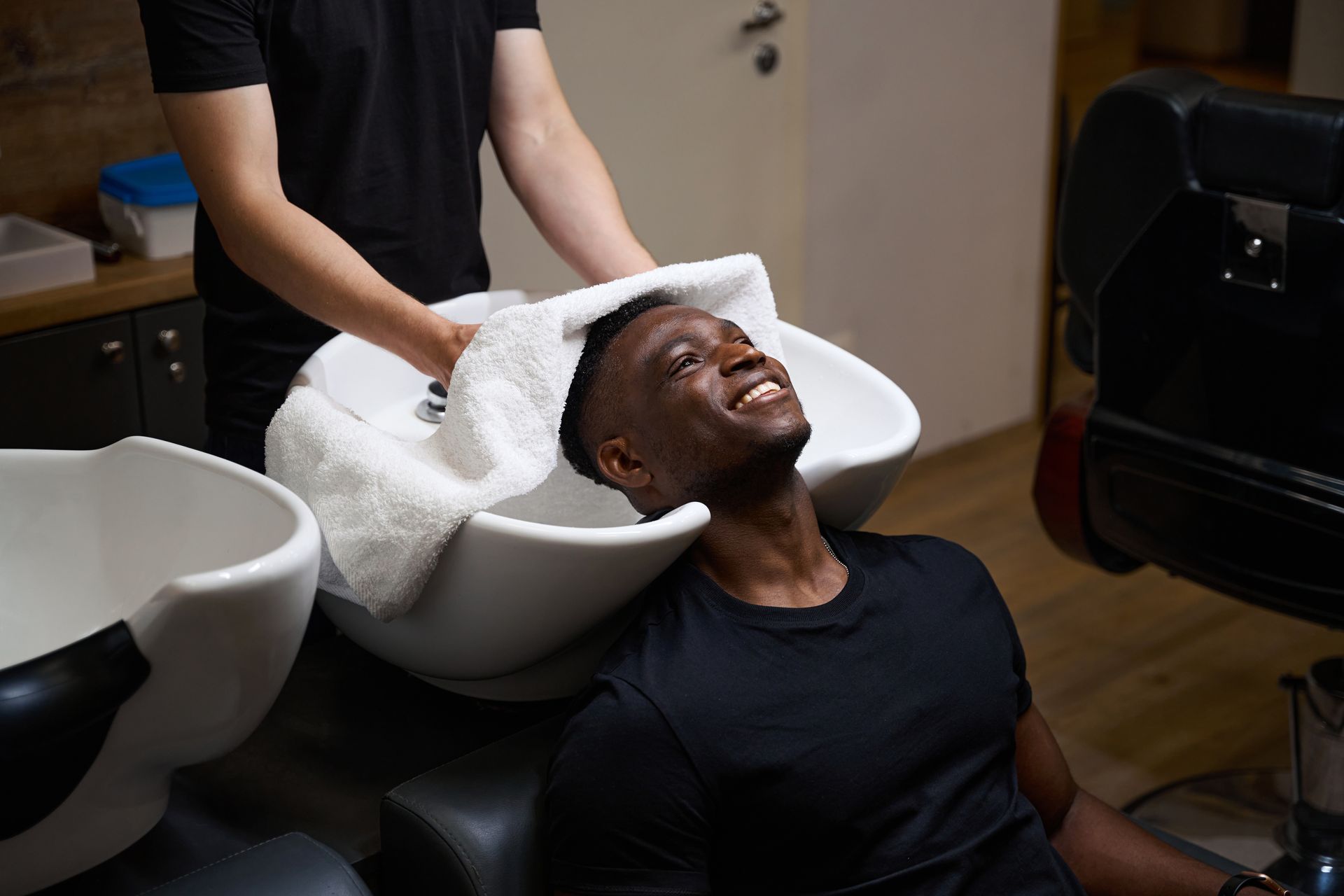 A man is getting his hair washed in a barber shop.