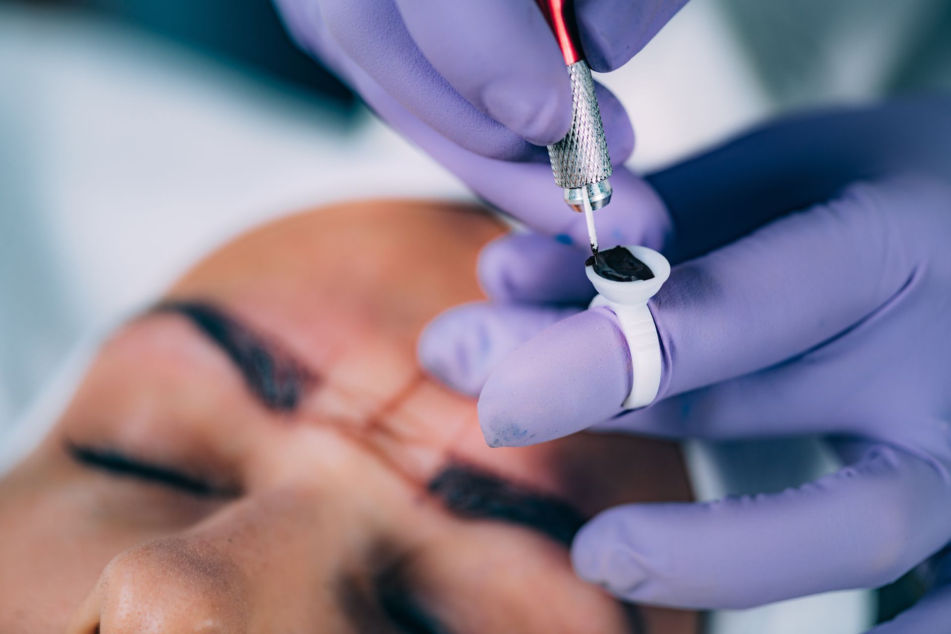 A woman is getting a tattoo on her eyebrows.