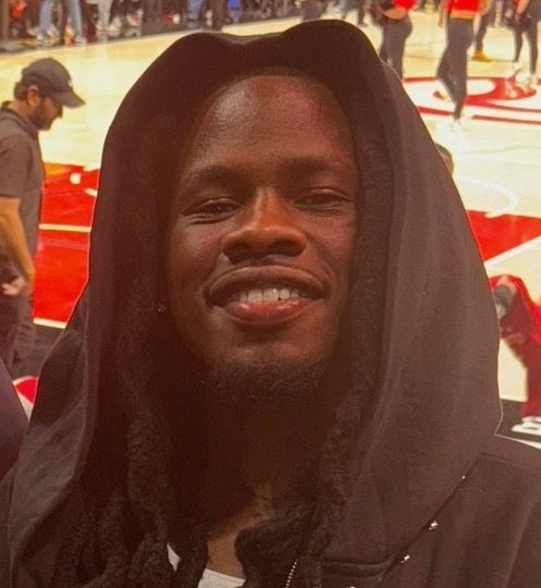 A man wearing a black hoodie is smiling for the camera