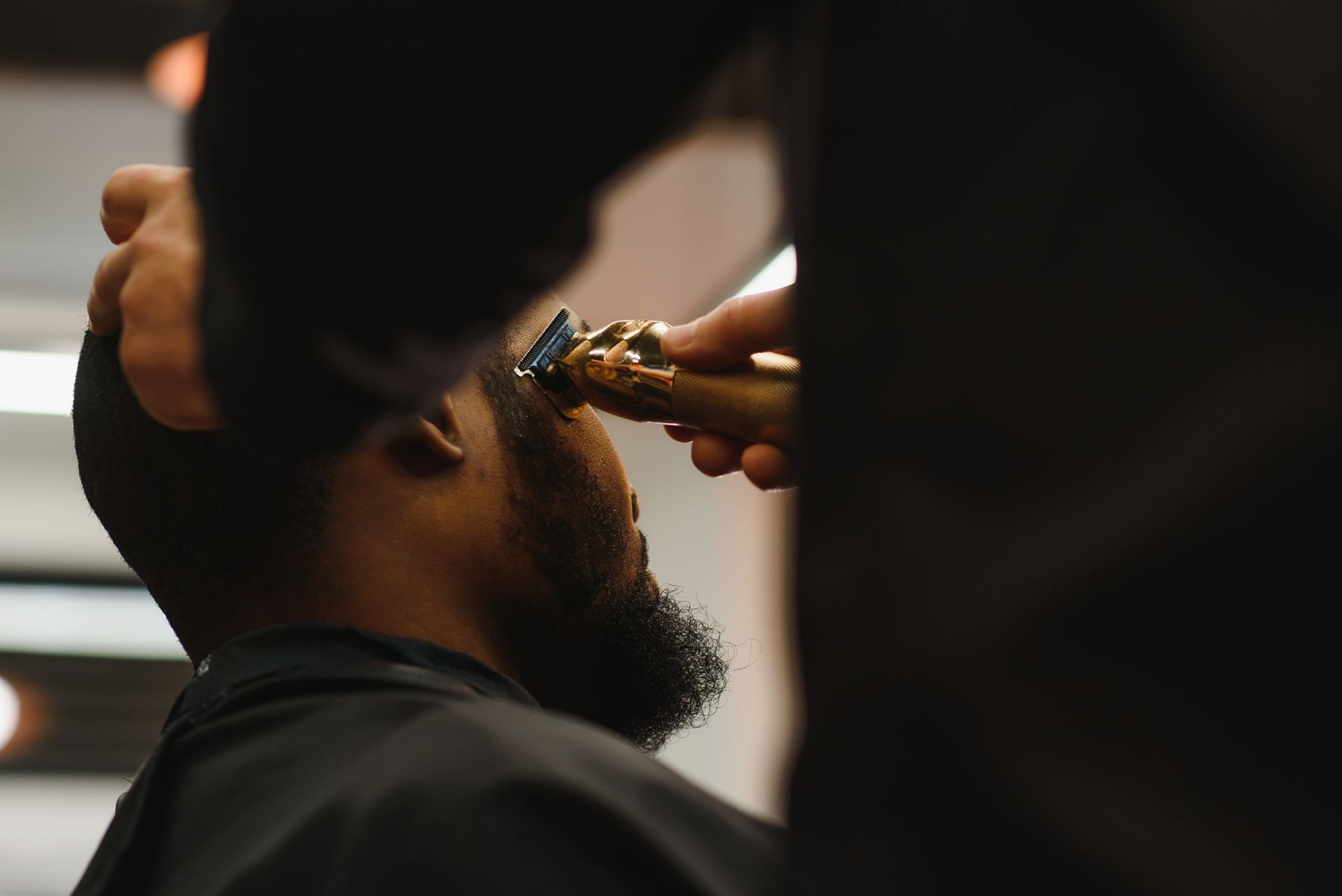 A man is getting his beard trimmed by a barber.