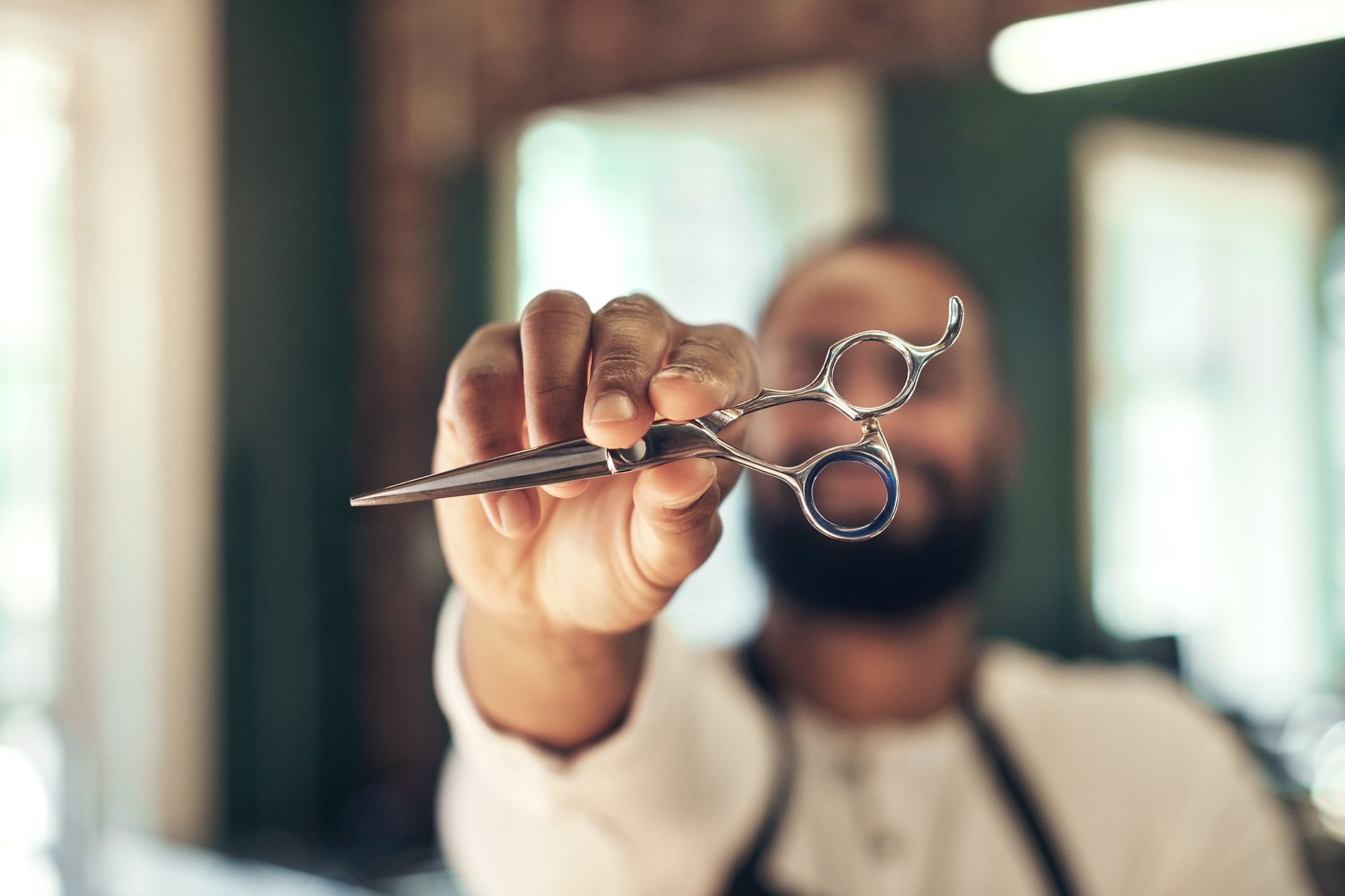 A barber is holding a pair of scissors in his hand.