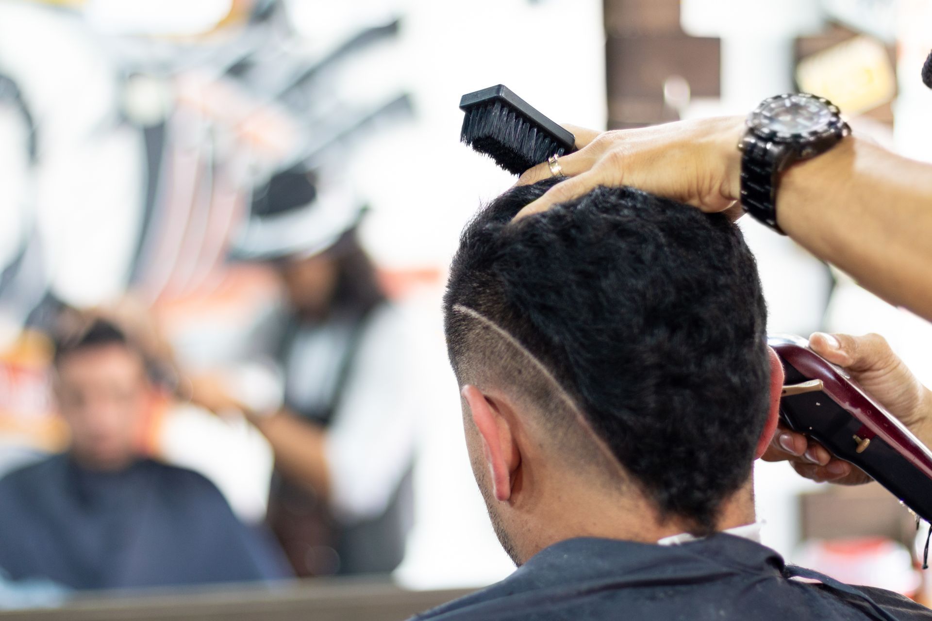 A man is getting his hair cut at a barber shop.