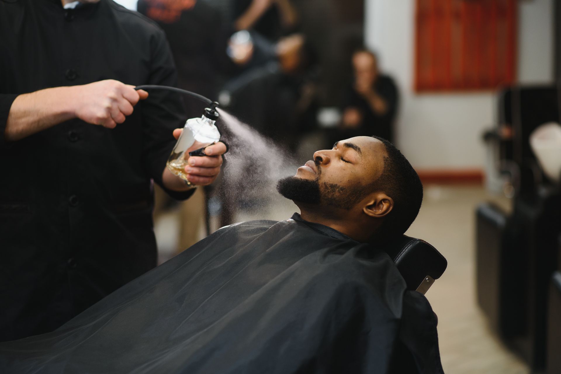 A man is getting his hair cut by a barber in a barber shop.