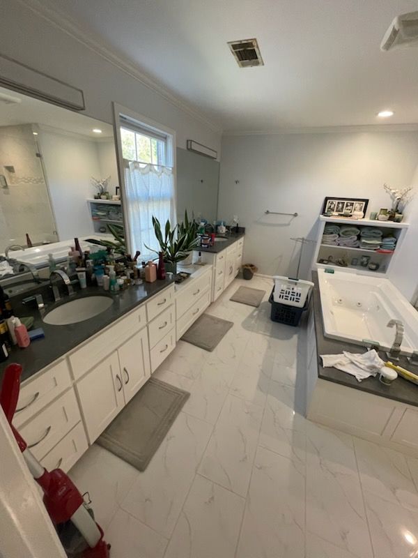 Bathroom with double vanity, bathtub, and white tile floor.