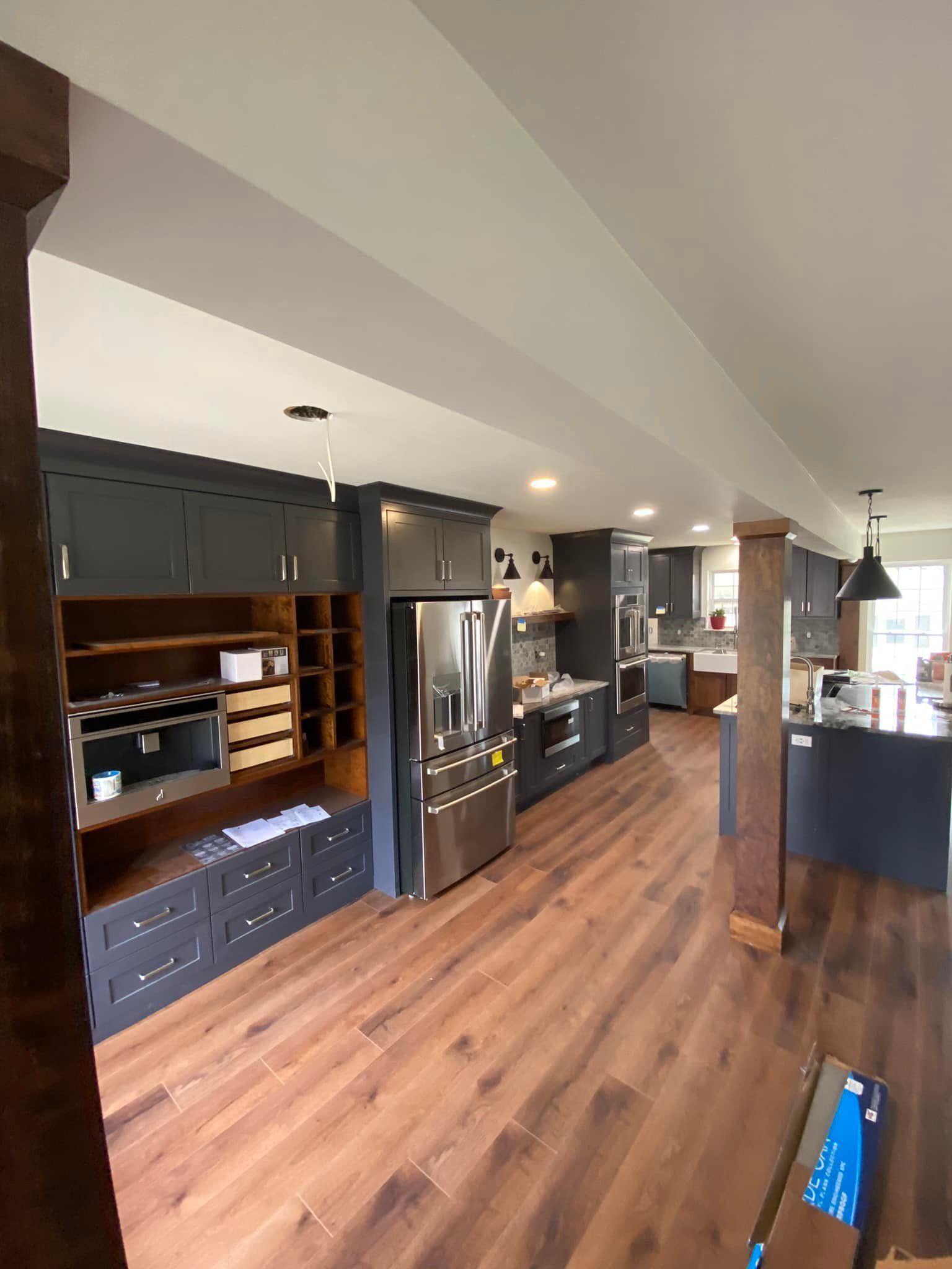Modern kitchen with gray cabinets, stainless steel appliances, and wood flooring.