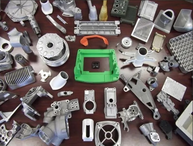 Assortment of manufactured metal and plastic parts laid out on a table, including gears, housings, and other components.