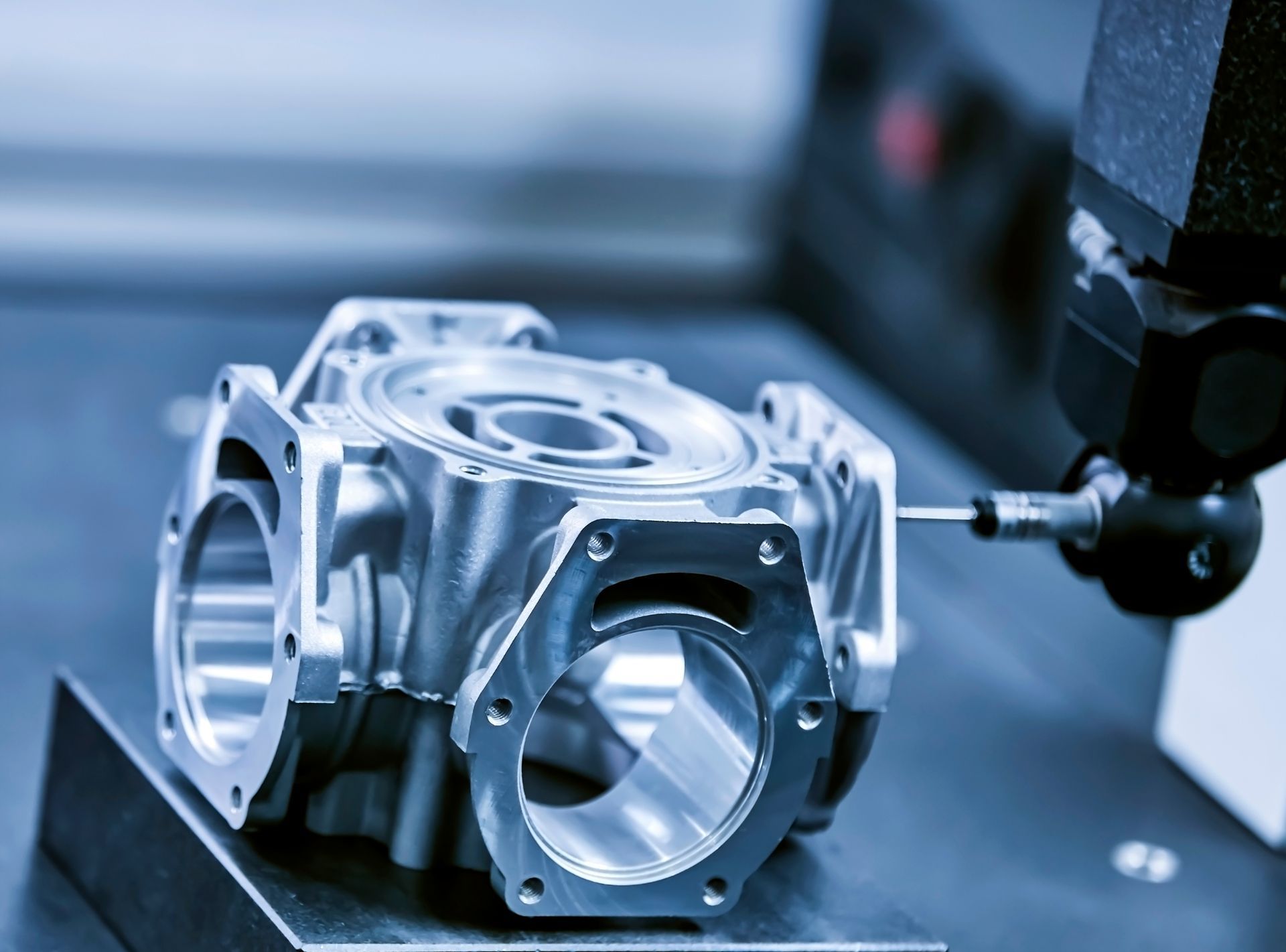 Metal component being measured by a CMM (Coordinate Measuring Machine) in a manufacturing setting.