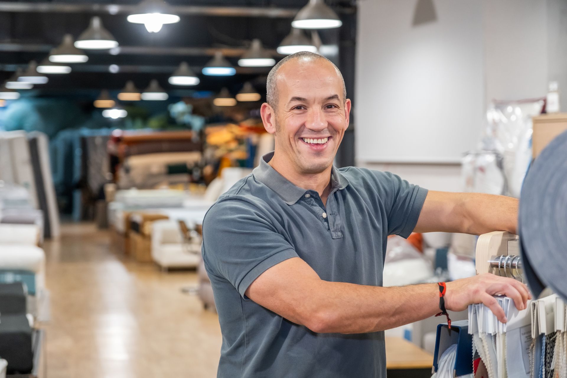 Man smiling in fabric store, reaching for fabric samples.