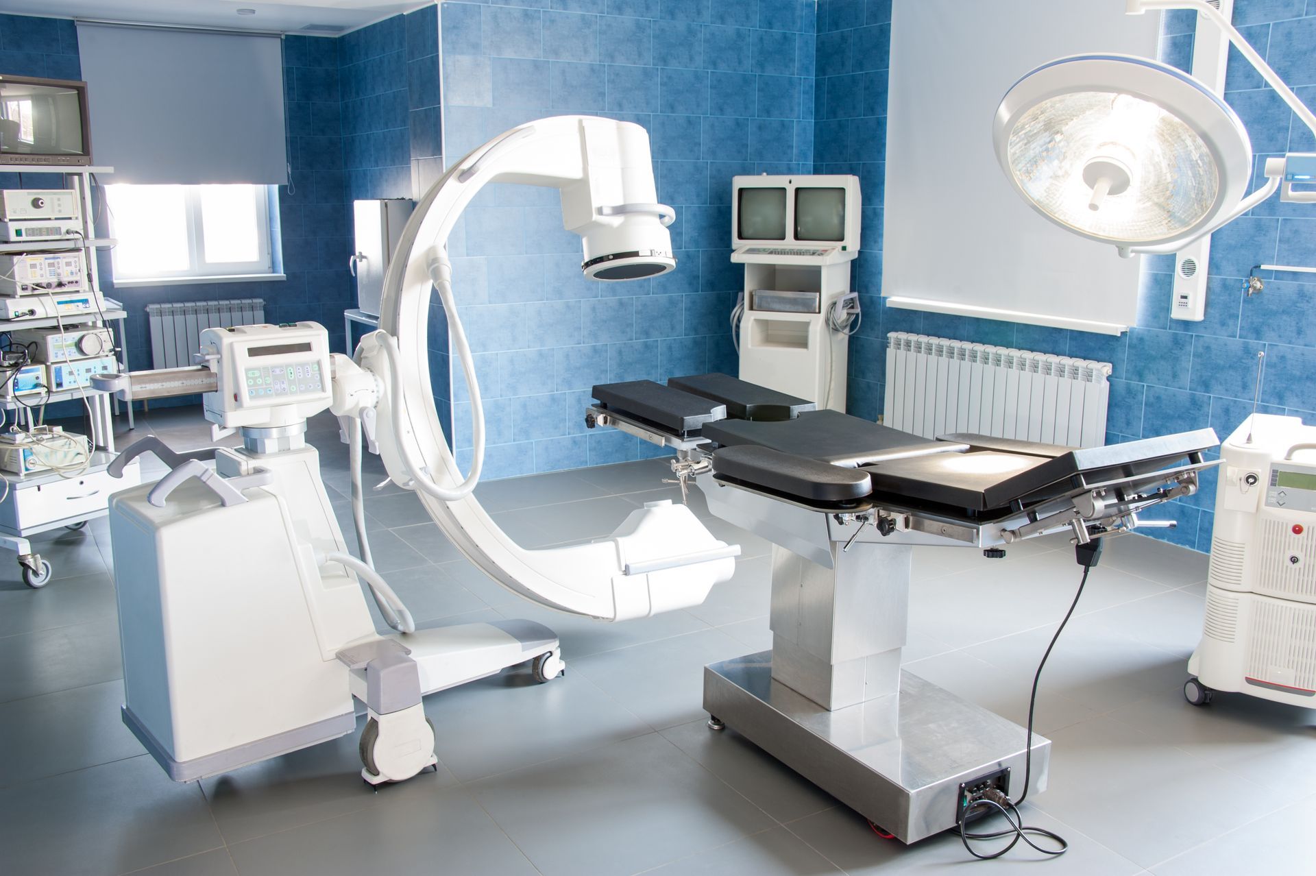 Operating room with surgical table, C-arm X-ray machine, and medical equipment.