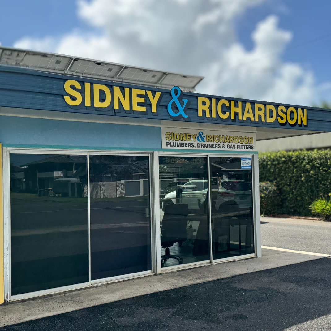 Sidney & Richardson real estate office storefront with blue signage and a yellow “HEATING” banner