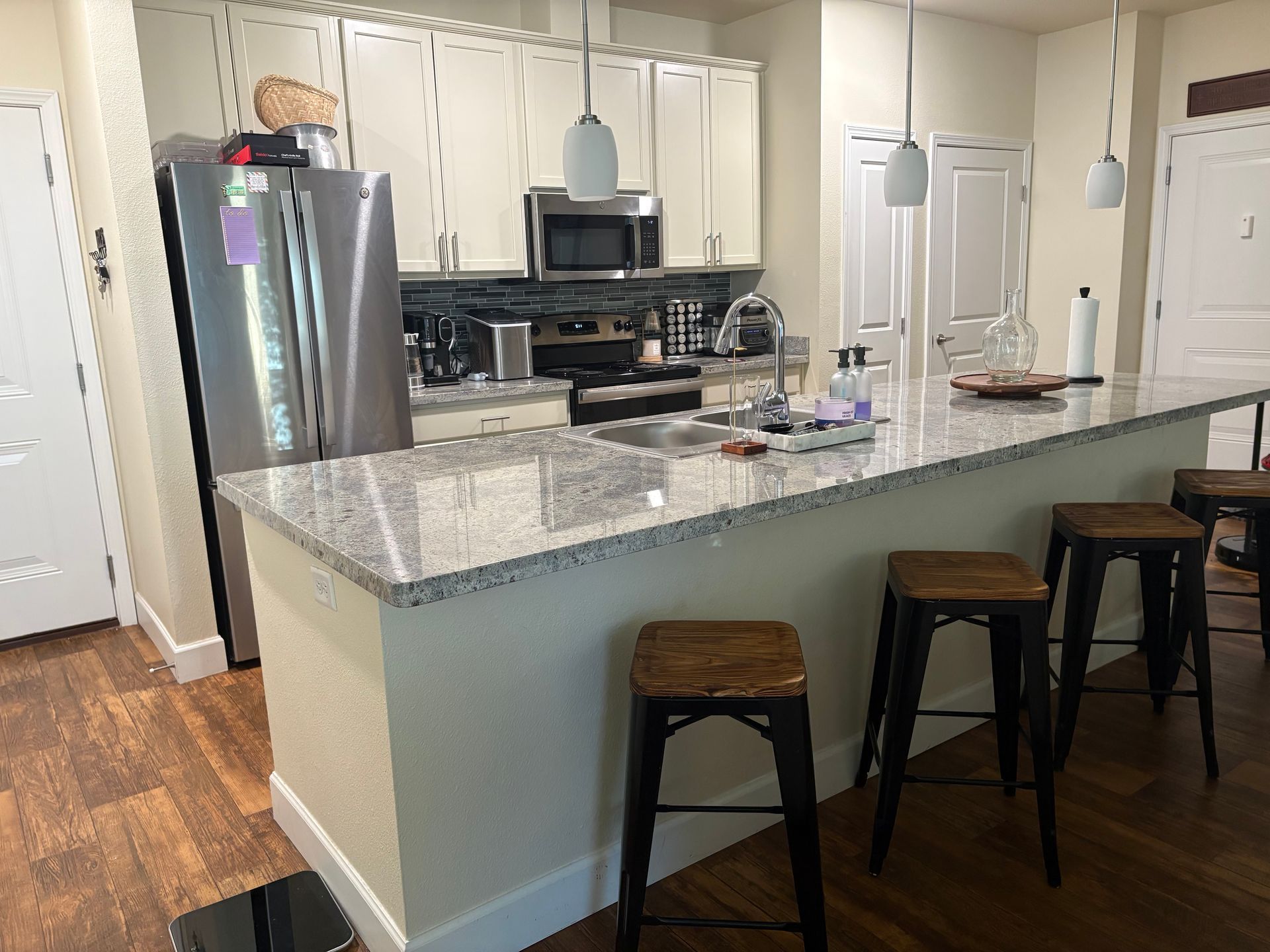 Kitchen with a breakfast bar, stainless steel appliances, and white cabinets.
