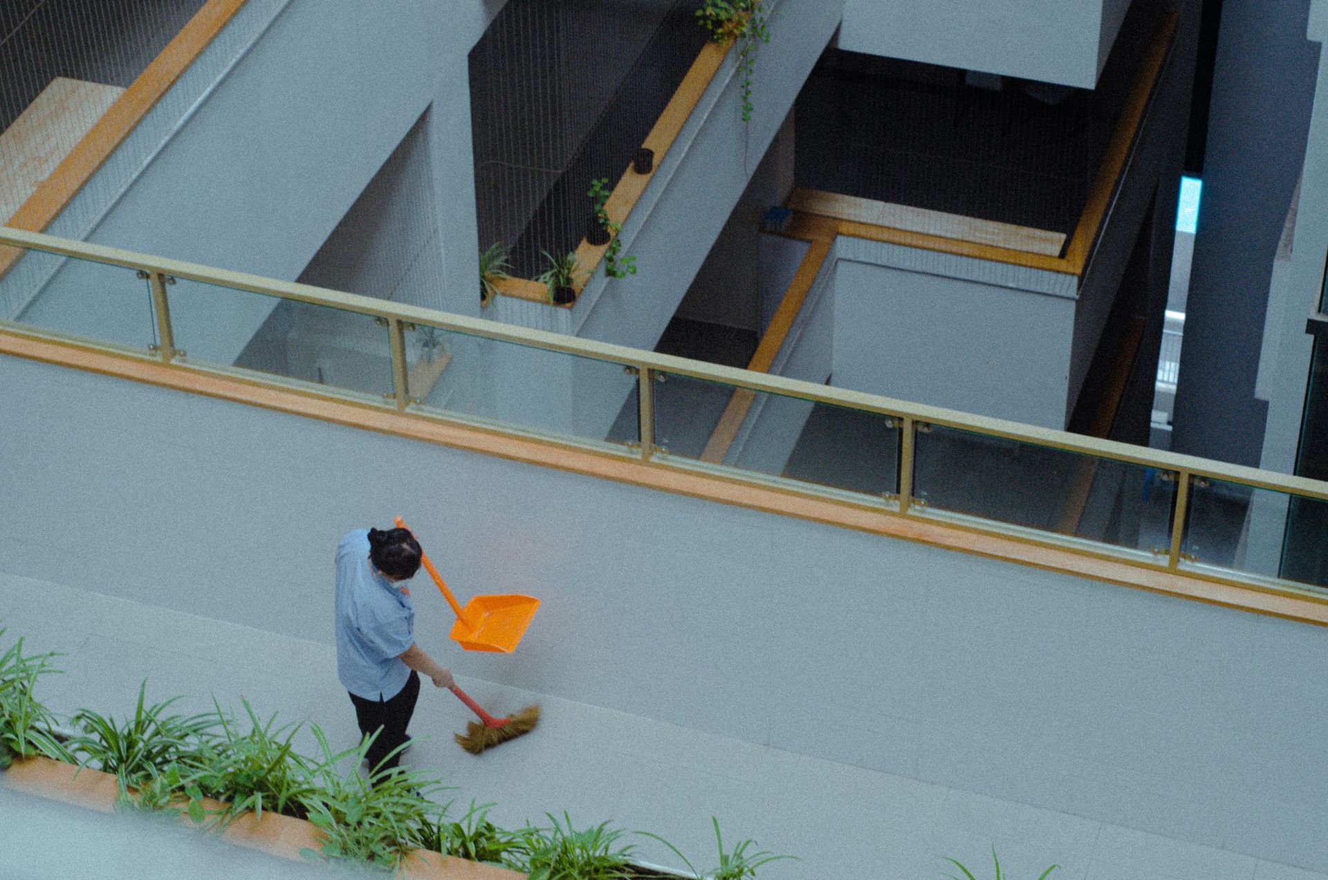 A man is sweeping the floor of a building with an orange broom