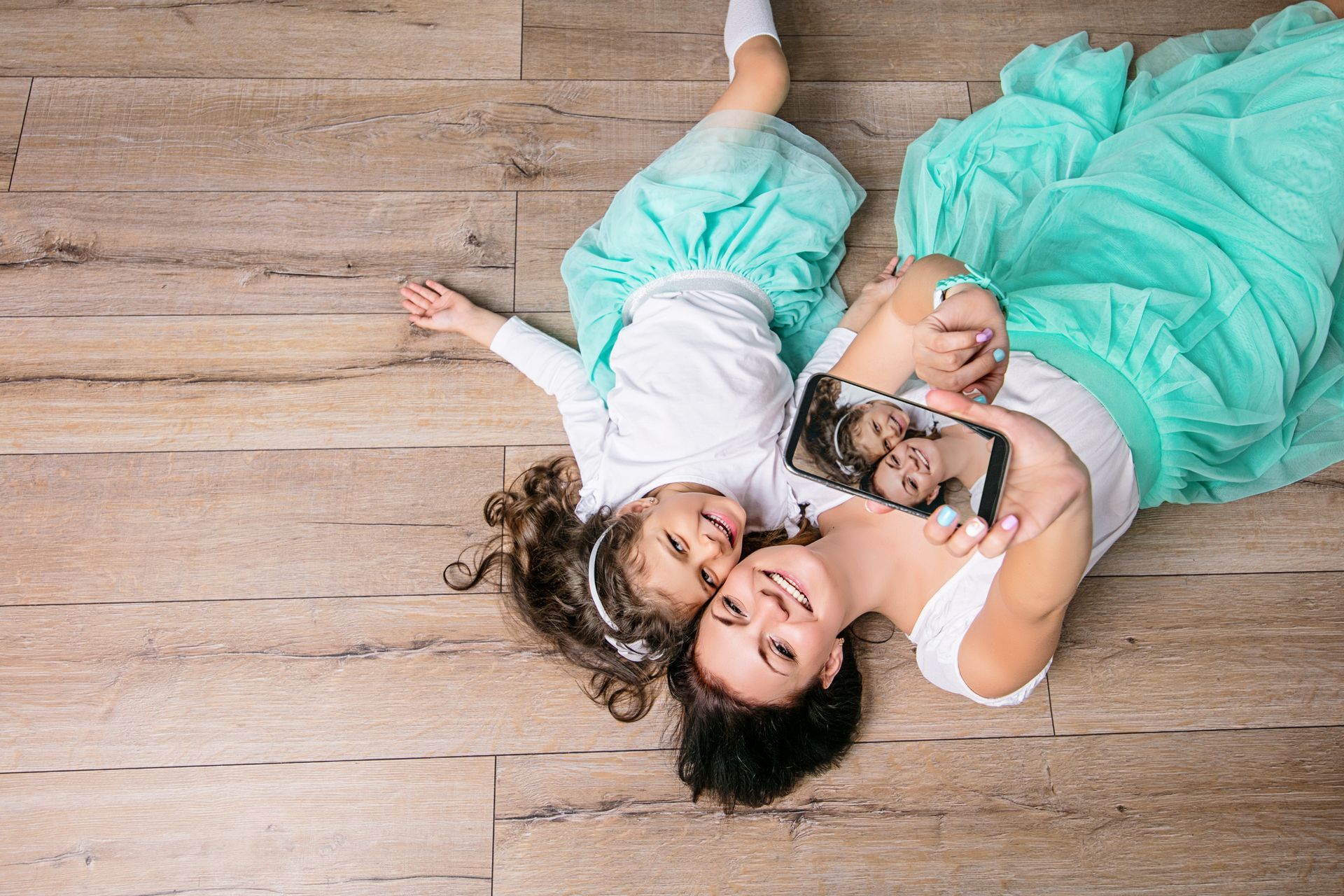 A woman and a little girl are laying on the floor.
