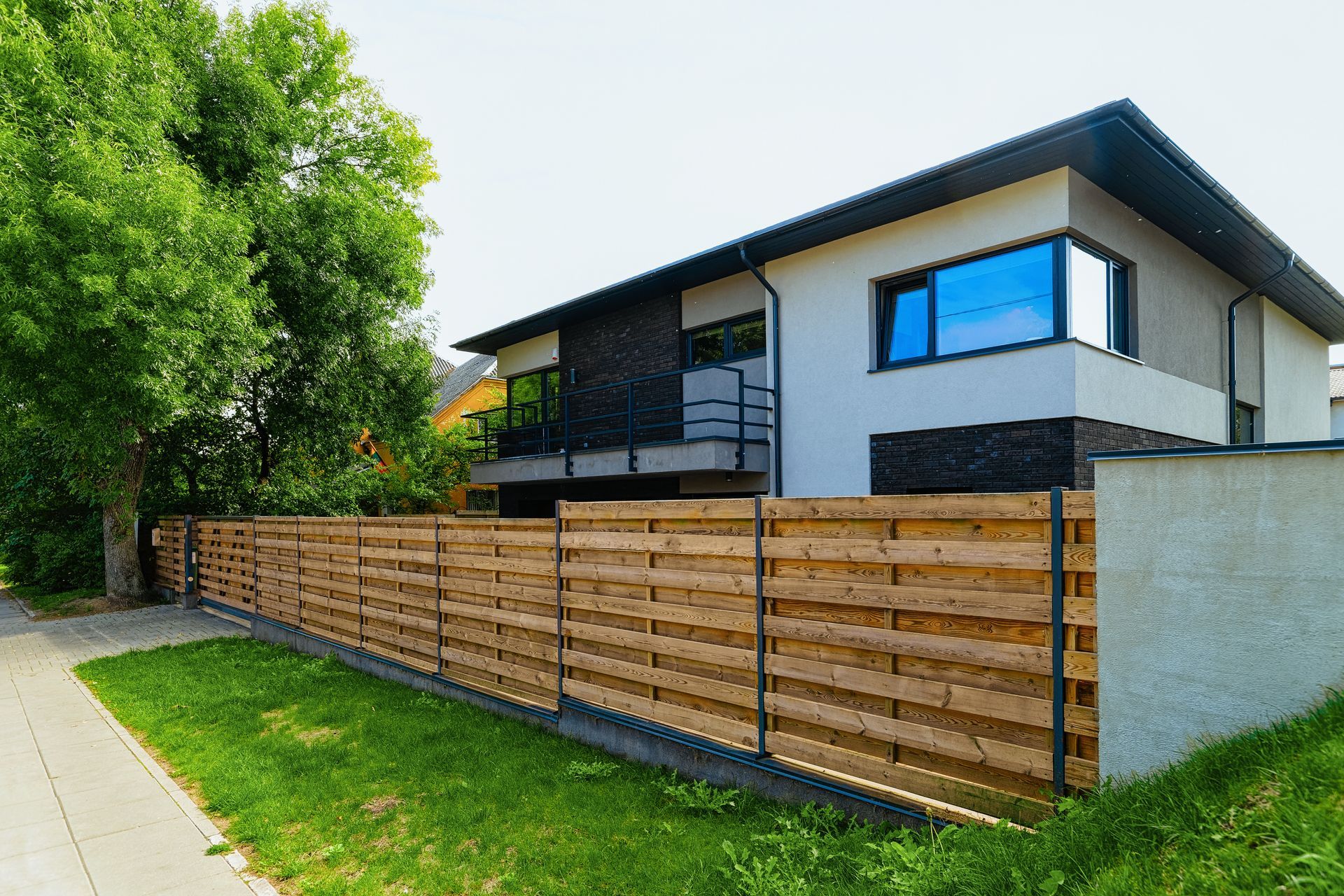 A modern house with a wooden fence in front of it.