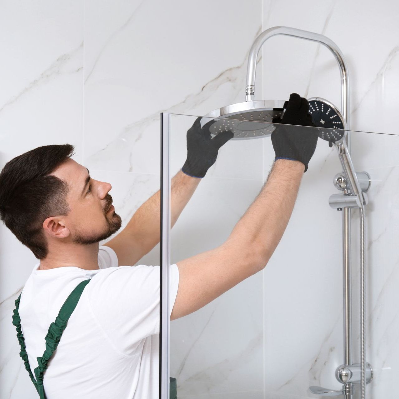 A man is installing a shower head in a bathroom.