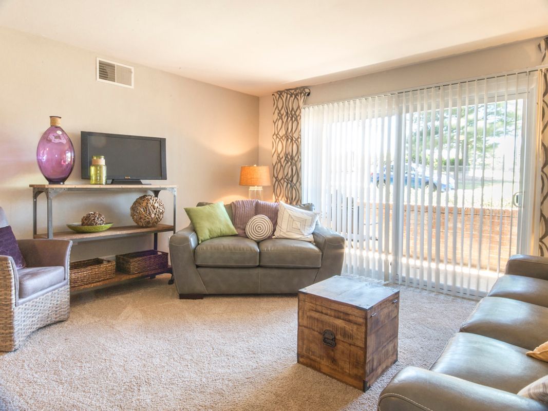 A living room with a couch , chair , television and sliding glass doors.