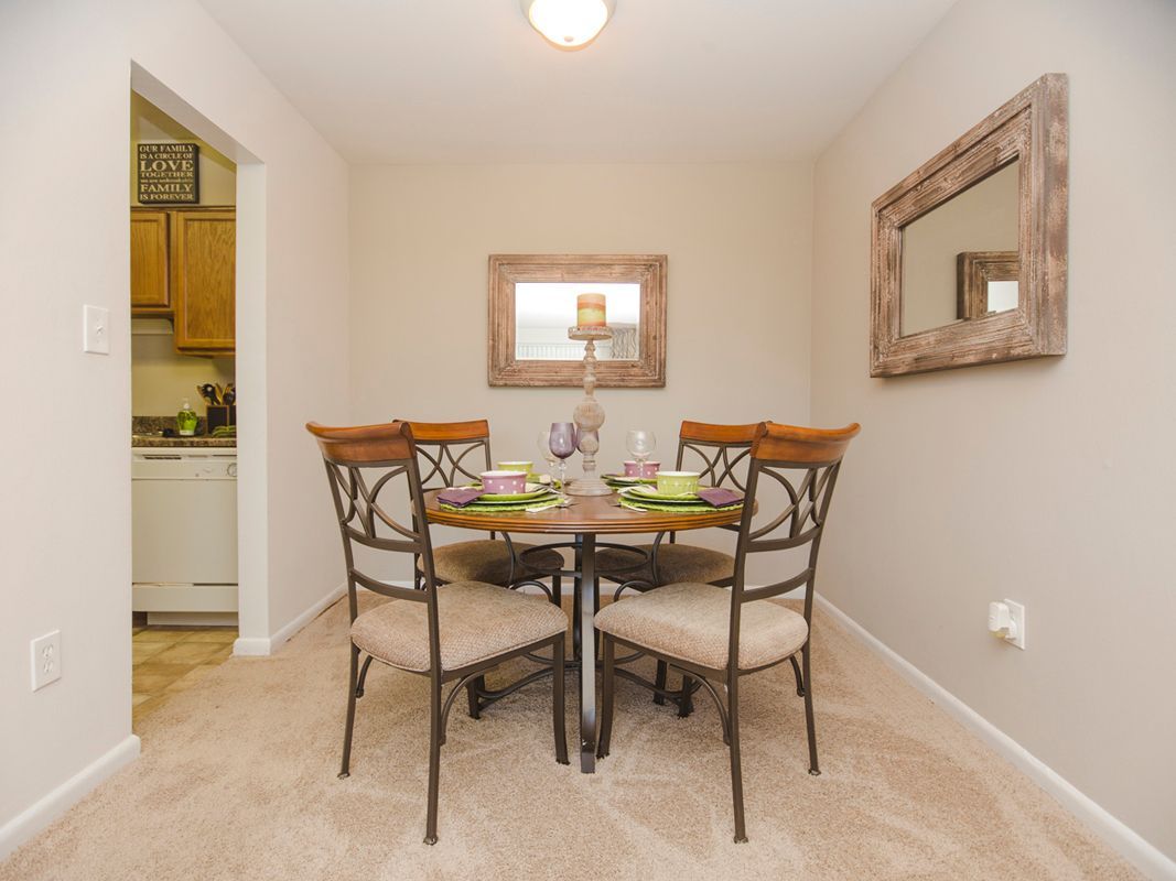 A dining room with a table and chairs and a mirror on the wall.