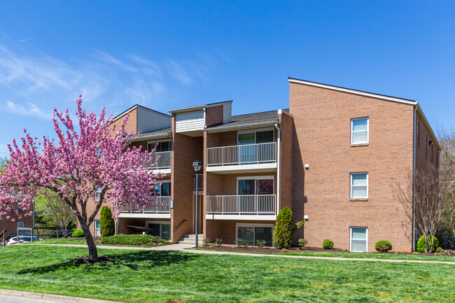 A large brick apartment building with a cherry blossom tree in front of it.