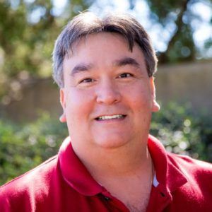 A man in a red shirt is smiling for the camera.